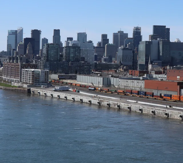Quai du port de Montréal avec des trains de conteneurs et le centre-ville en arrière-plan